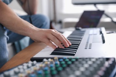 İçerideki masada MIDI klavyesiyle çalışan adam, yakın plan.