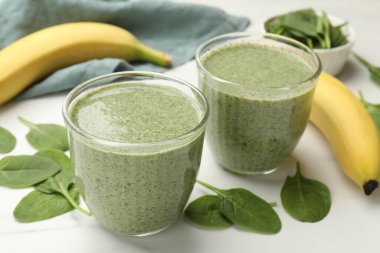 Lezzetli ıspanaklı smoothie ve malzemeler beyaz masada, yakın plan.