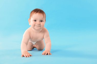 Açık mavi arka planda emekleyen şirin bir bebek. Metin için boşluk