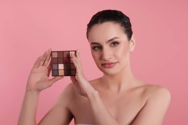 Pembe arka planda göz falı paleti olan kadın.