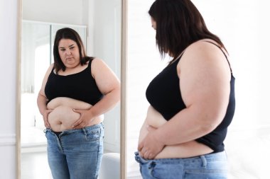 İçeride aynanın yanında göbeği aşırı yağlı bir kadın var. Aşırı kilolu