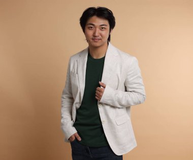 Bej arka planda takım elbiseli yakışıklı Asyalı işadamının portresi