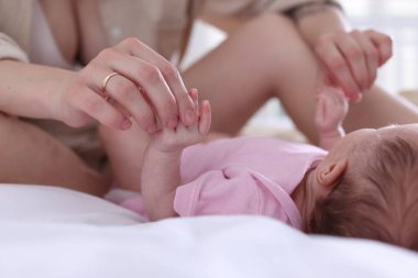 Anne yeni doğmuş bebeğiyle evde, yatakta, yakın plan.