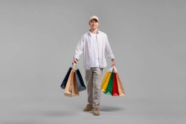 Açık gri arka planda alışveriş torbaları olan neşeli bir adam.