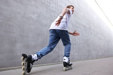 Mutlu genç adam sokakta kayıyor, alçak açılı.