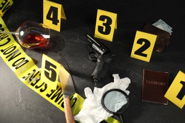 Adli tıp uzmanı. Sarı olay yeri bandı, siyah masanın üstünde işaretler ve kanıtlar var.