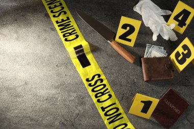 Adli tıp uzmanı. Sarı olay yeri bandı, kanıt işaretleri, para dolu cüzdan, gri masanın üstünde bıçak ve pasaport. Metin için boşluk