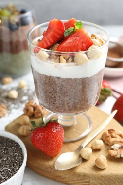 Chia tohumlu çikolatalı puding, çilek, yoğurt ve fındıklar beyaz masada, yakın plan.