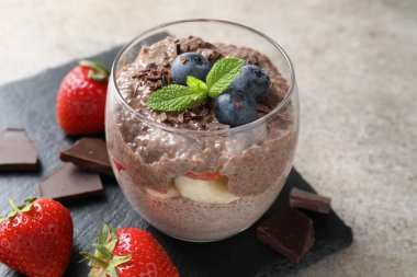 Çikolatalı puding, chia tohumu, çilek ve böğürtlen açık gri masada, yakın plan.