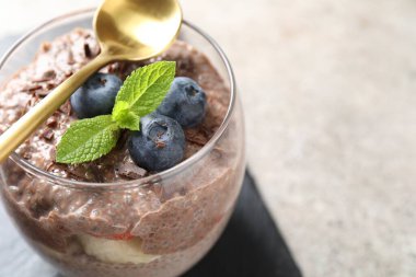 Açık gri masada bardakta yaban mersini ve chia tohumlu lezzetli çikolatalı puding, yakın plan. Metin için boşluk