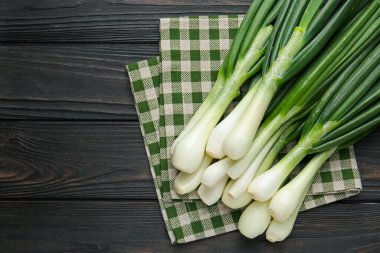 Taze taze soğan ve siyah ahşap masa üzerinde havlu, üst manzara. Metin için boşluk