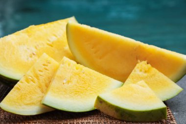 Yüzme havuzunun yanındaki masada olgun sarı karpuz parçaları, yakın plan.