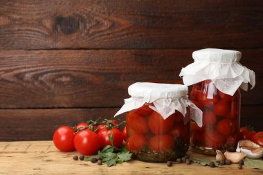 Kavanozlarda domates turşusu, taze ürünler ve ahşap masada baharatlar, yakın plan. Metin için boşluk