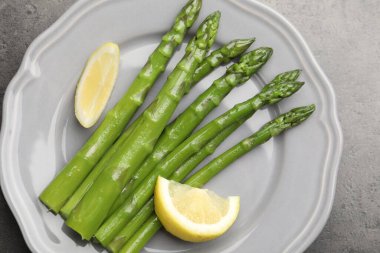 Gri masada limonla servis edilen lezzetli pişmiş kuşkonmaz.