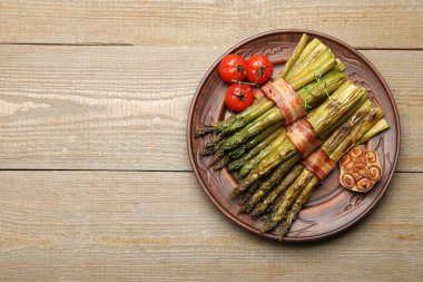 Ahşap masada domuz pastırması ve baharatla servis edilen lezzetli pişmiş kuşkonmaz. Metin için boşluk