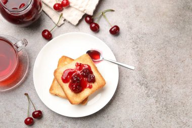 Lezzetli kiraz reçelli tostlar, çay ve gri masada taze meyveler, düz yatak. Metin için boşluk