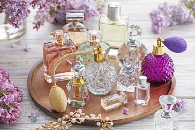 Beyaz ahşap masada parfüm, aksesuar ve leylak çiçekleri.