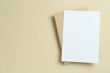 Bej arka planda boş davetiye ve zarf, üst manzara. Tasarım için boşluk