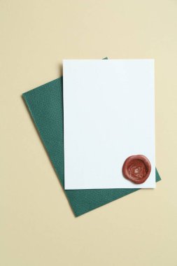 Üzerinde balmumu mühür olan boş bir davetiye kartı ve bej arka planı olan bir zarf. Tasarım için boşluk
