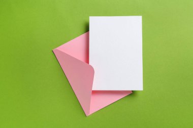 Yeşil arka planda boş davetiye ve zarf, üst manzara. Tasarım için boşluk