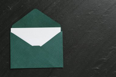 Boş davetiye kartı ve zarf siyah masanın üstünde, en üstte. Metin için boşluk