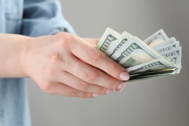 Açık gri arka planda dolar banknotları sayan kadın, yakın plan