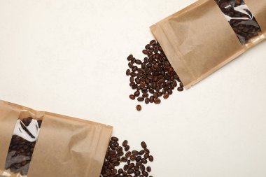 Fermuarlı stand-up paketleri ve kahve çekirdekleri beyaz masada, düz yerde. Tasarım için model