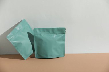 Açık gri arka plana karşı bej masadaki fermuar stand-up kesesi, tasarım için model