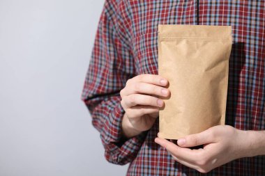 Açık gri arka planda fermuarlı stand-up çantası tutan kadın, yakın plan. Metin için boşluk