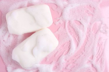 Pembe arka planda köpüklü sabun kalıpları, düz yatış. Metin için boşluk