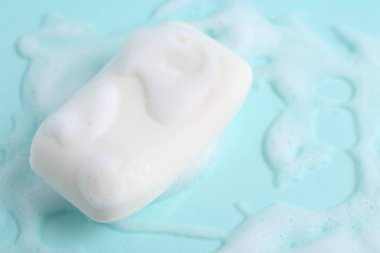 Açık mavi arka planda köpüklü sabun çubuğu. Metin için boşluk