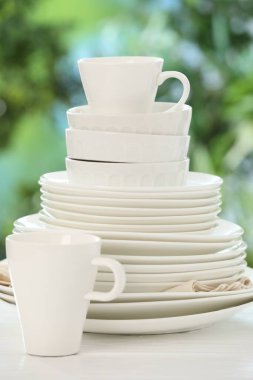 Bulanık yeşil arka planda beyaz masada farklı temiz tabaklar