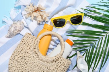 Plaj aksesuarları, deniz kabukları ve açık mavi arka planda palmiye yaprağı, düz uzanmış.
