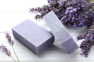 Sabun barları ve lavanta çiçekleri beyaz ahşap masada, yakın plan.