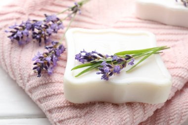 Sabun çubuğu, lavanta çiçekleri ve havlu beyaz masada, yakın plan.