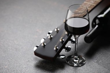 Akustik gitar ve kırmızı şarap siyah masada, yakın plan. Metin için boşluk