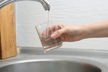 Bardağı kirli musluk suyuyla dolduran kadın, yakın plan.