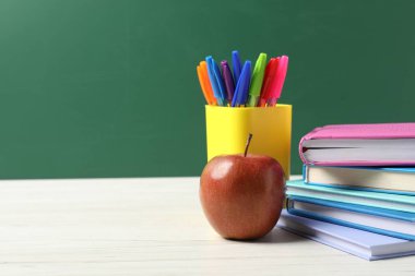 Farklı okul kırtasiyesi ve beyaz ahşap masada kırmızı elma karatahtaya karşı, yazı için yer