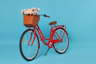 Açık mavi arka planda güzel çiçeklerle dolu bir bisiklet sepeti