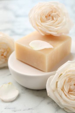Sabun çubuğu ve çiçekler beyaz mermer masada, yakın plan.