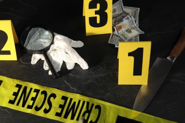 Adli tıp uzmanı. Sarı olay yeri bandı, siyah masanın üstünde işaretler ve kanıtlar var.