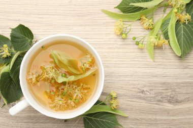 Taze ıhlamur çayı fincanda, çiçekler ahşap masada, düz yerde. Metin için boşluk