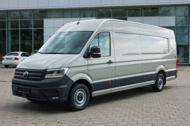 Asfalt yolda park etmiş beyaz bir minibüs.