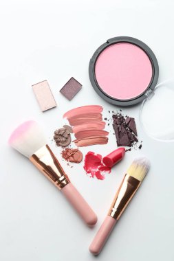 Beyaz arka planda farklı kozmetik ürünler ve makyaj fırçaları, düz yatış
