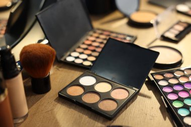 Ahşap masada farklı makyaj ürünleri, yakın plan.