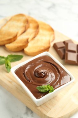 Lezzetli çikolata, parçalar, tost, nane ve fındıklar beyaz mermer masada, yakın plan.