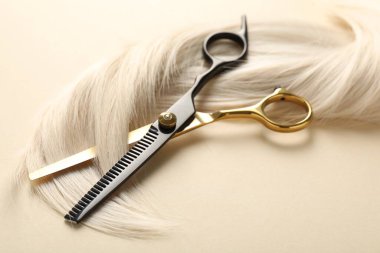 Bej arkaplanda saç tokası ve makas, yakın plan.