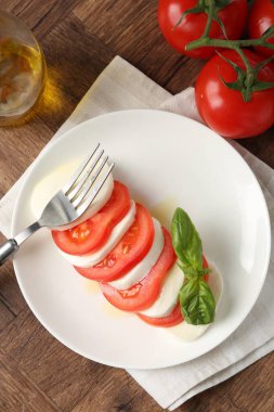 Lezzetli mozzarella, domates, yağ ve fesleğen ahşap masa, düz yatıyordu.