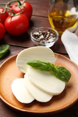 Lezzetli mozzarella, domates ve fesleğen ahşap masada, yakın plan.