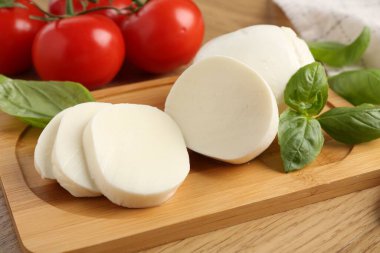 Lezzetli mozzarella, domates ve fesleğen ahşap masada, yakın plan.